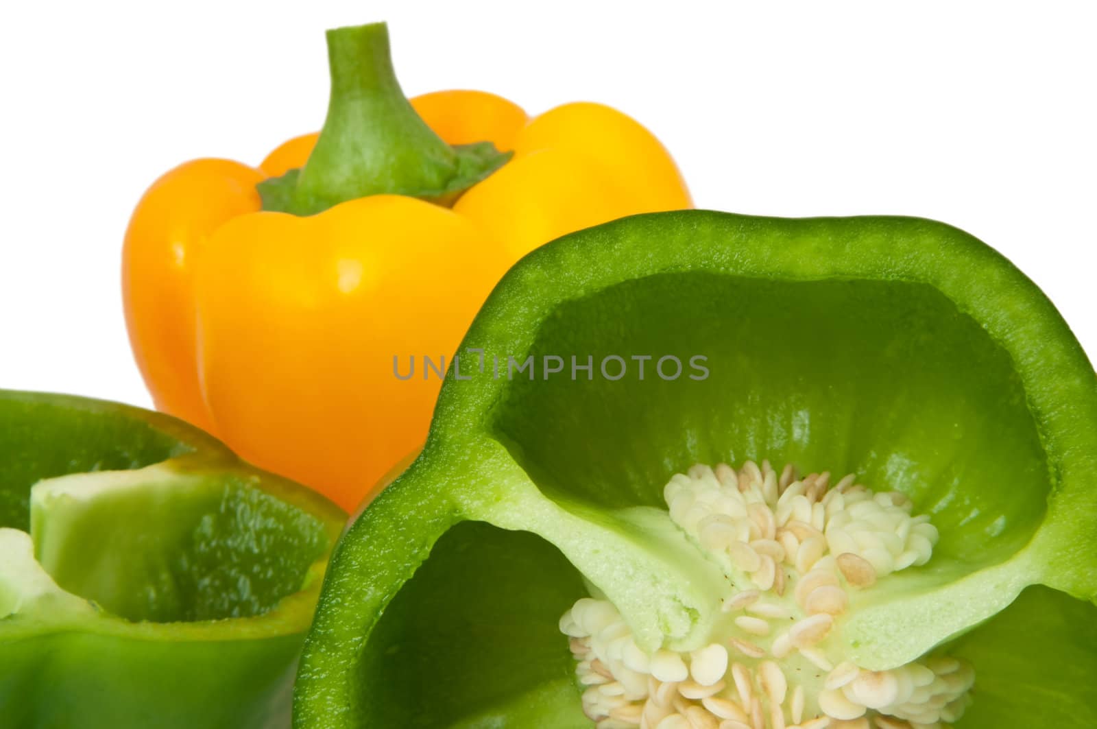 Close up capturing whole and halved bell peppers arranged over white.