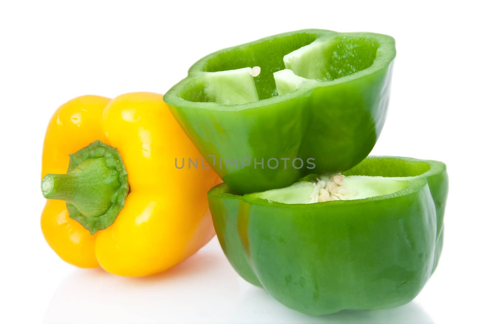 Close up capturing a small selection of whole and halved bell peppers arranged over white.