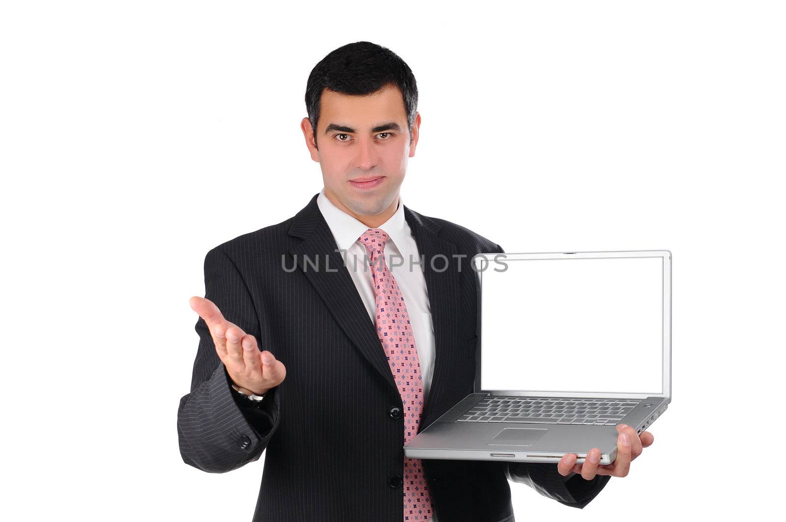 Portrait of a confident young businessman in a dark suit holding laptop and pointing his hand on screen isolated on white