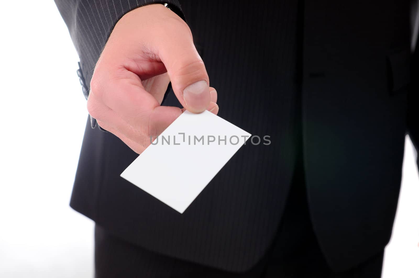 Businessman in a dark suit smiling and handing a business card isolated on white