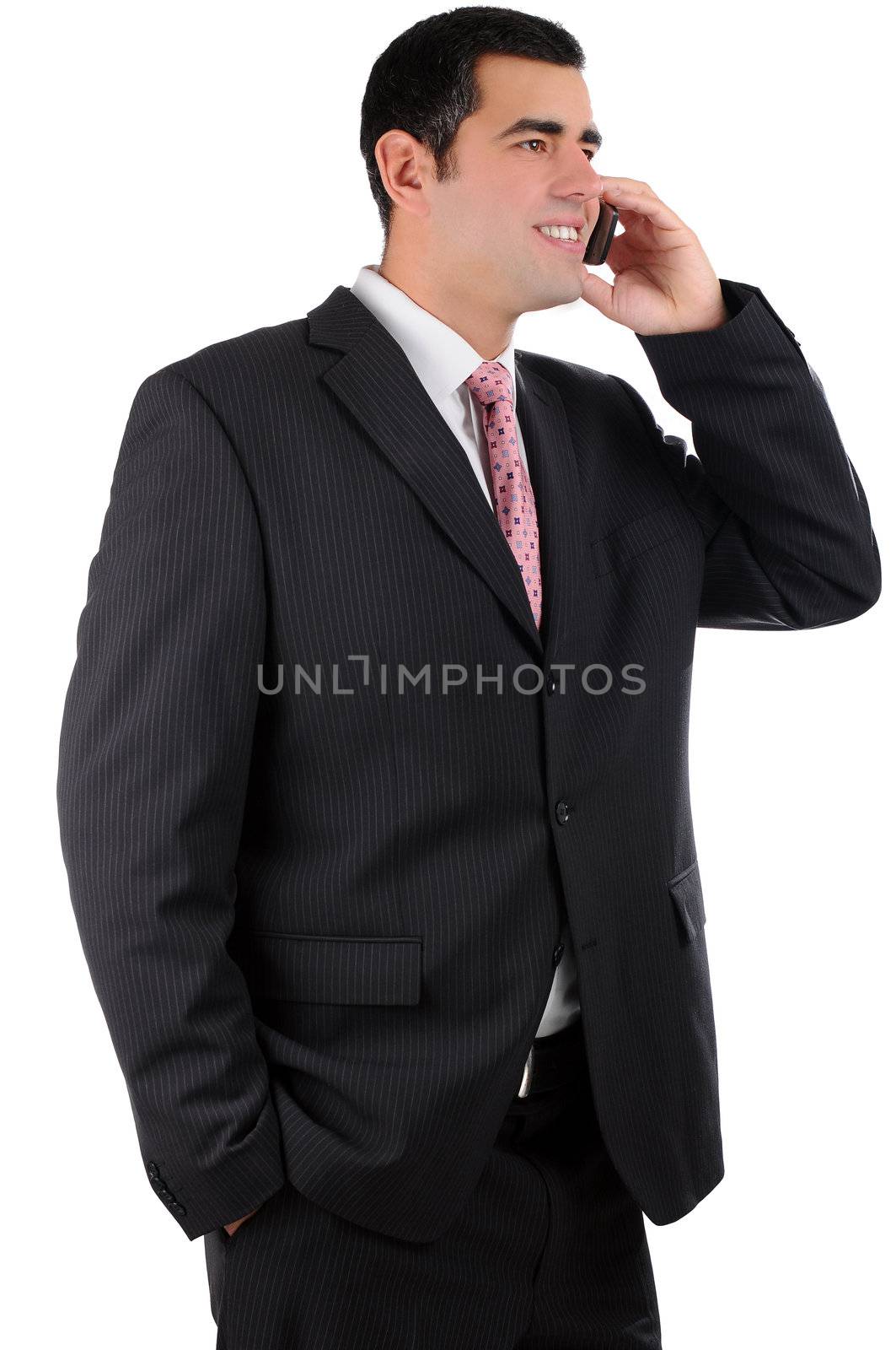 Portrait of a confident cheerful young businessman in a dark suit communicating using mobile phone isolated on white