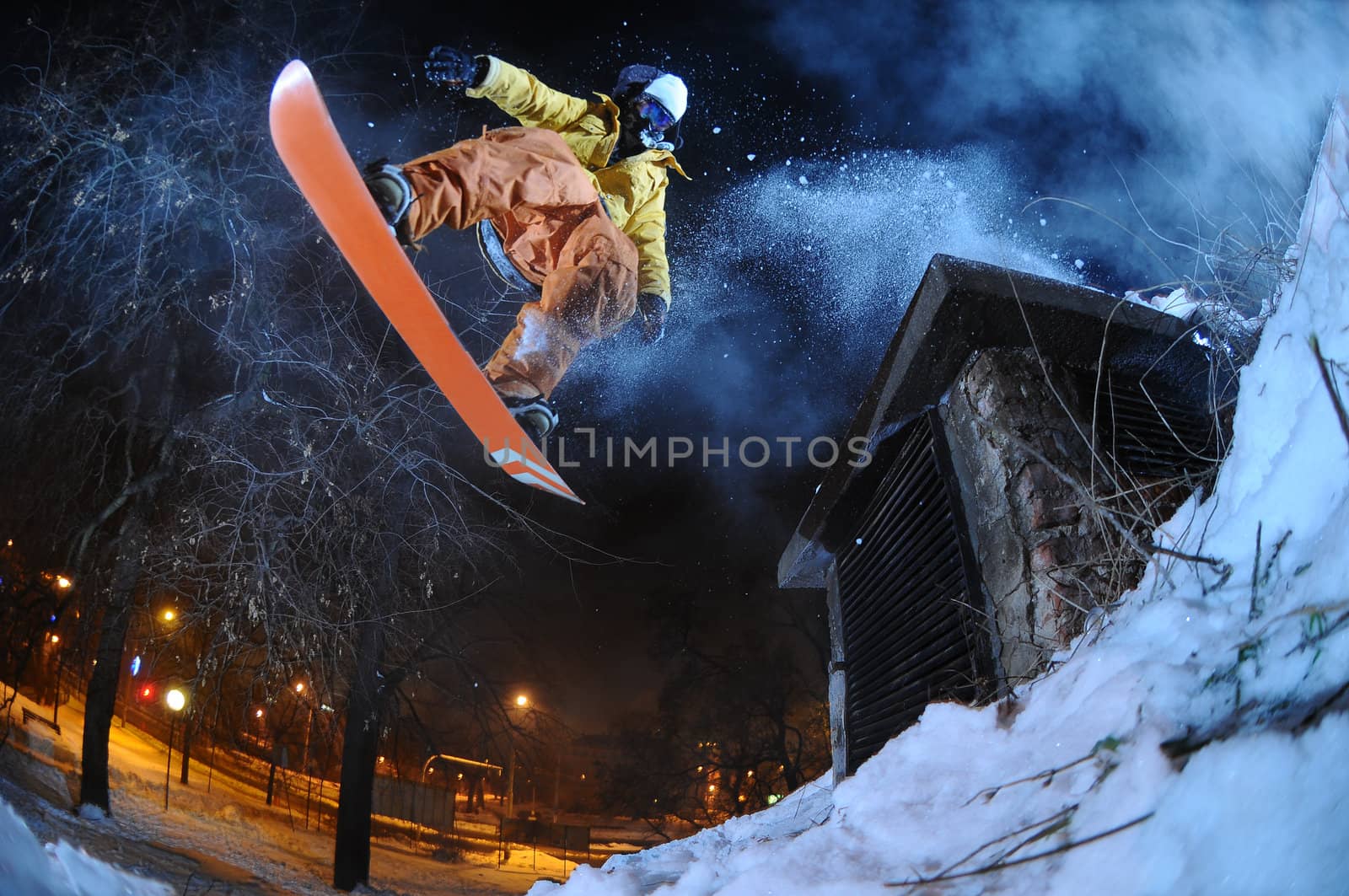 Jumping snowboarder in the city at night in winter by gravityimaging1