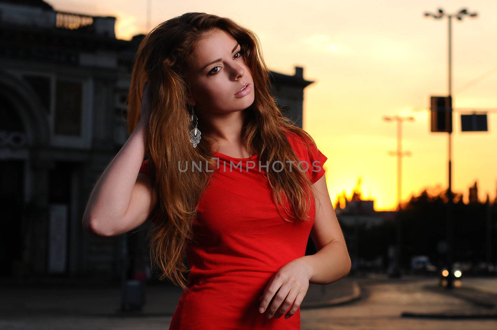 Portrait of a young attractive woman in a red dress in the city at dusk by gravityimaging1