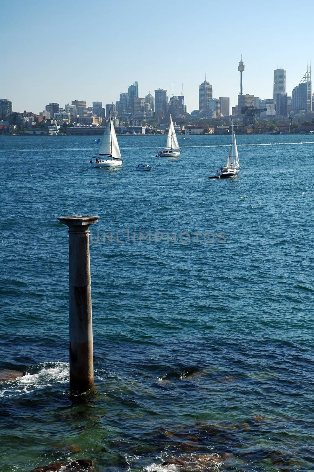 stone column in water, white yachts and sydney tower