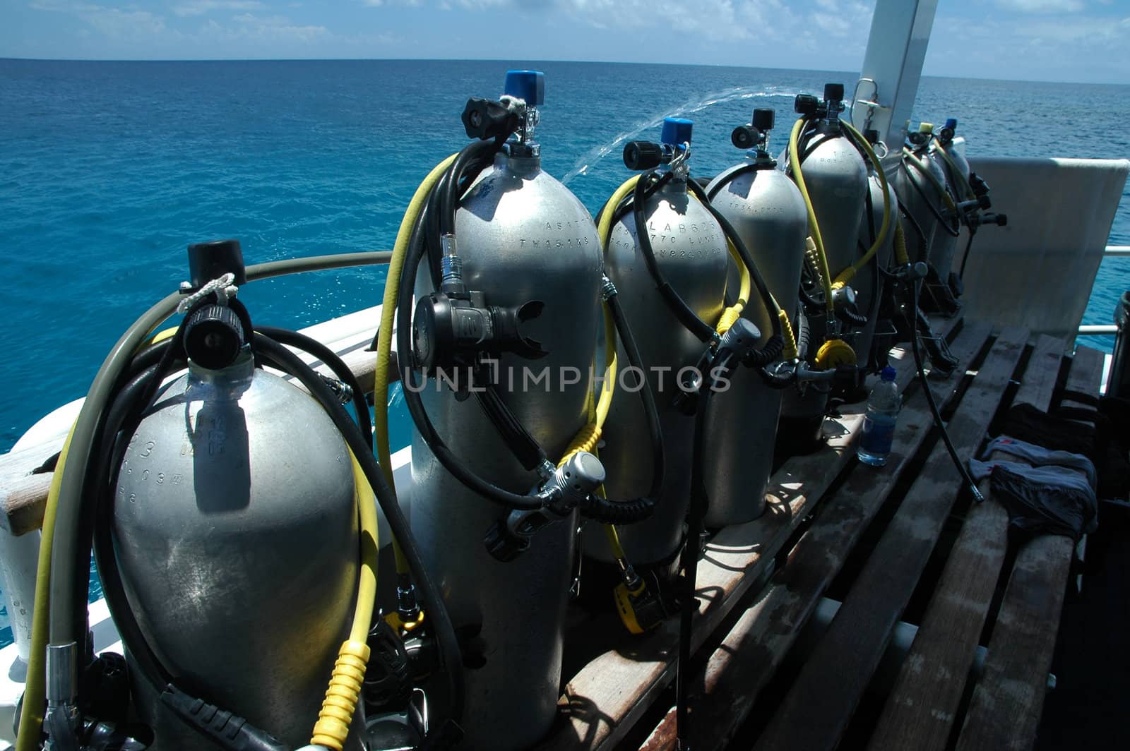 several scuba cylinders on boat, ocean in background