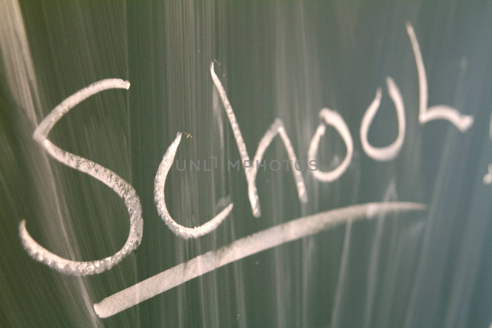 Closeup of the word "school" written on a green blackboard.