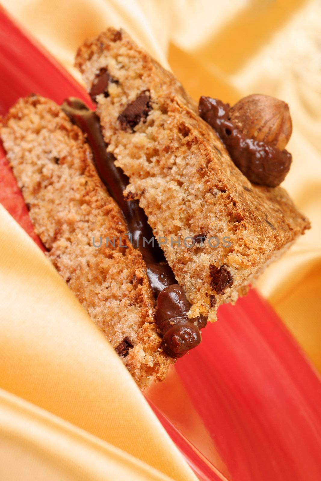 Slice of hazelnut and chocolate cream cake served on a red plate over a yellow background.