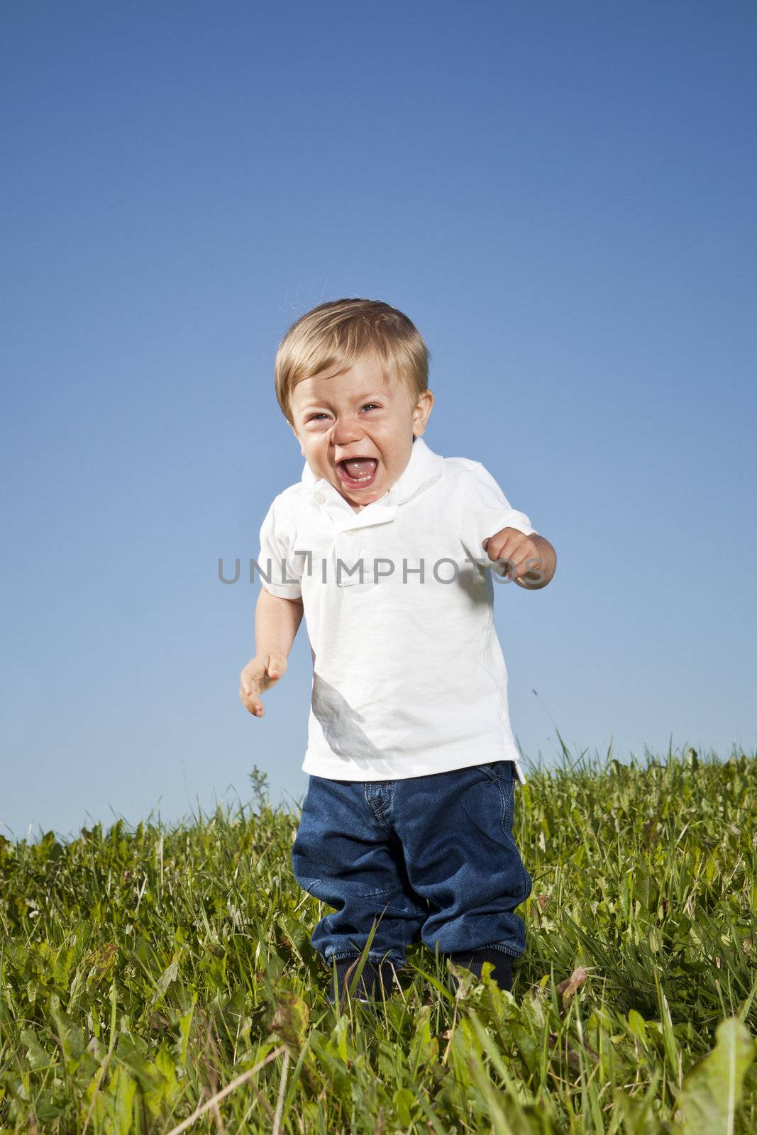 Crying child standing in the grass