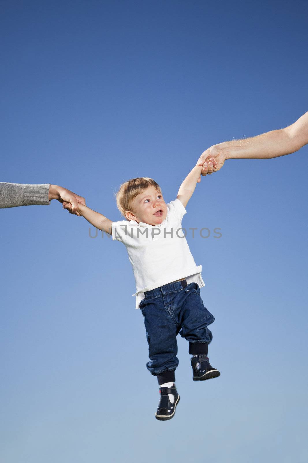 Child hanging in the air between parents hands