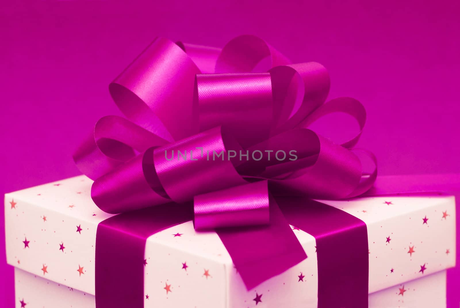 White christmas gift box with purple ribbon on pink background