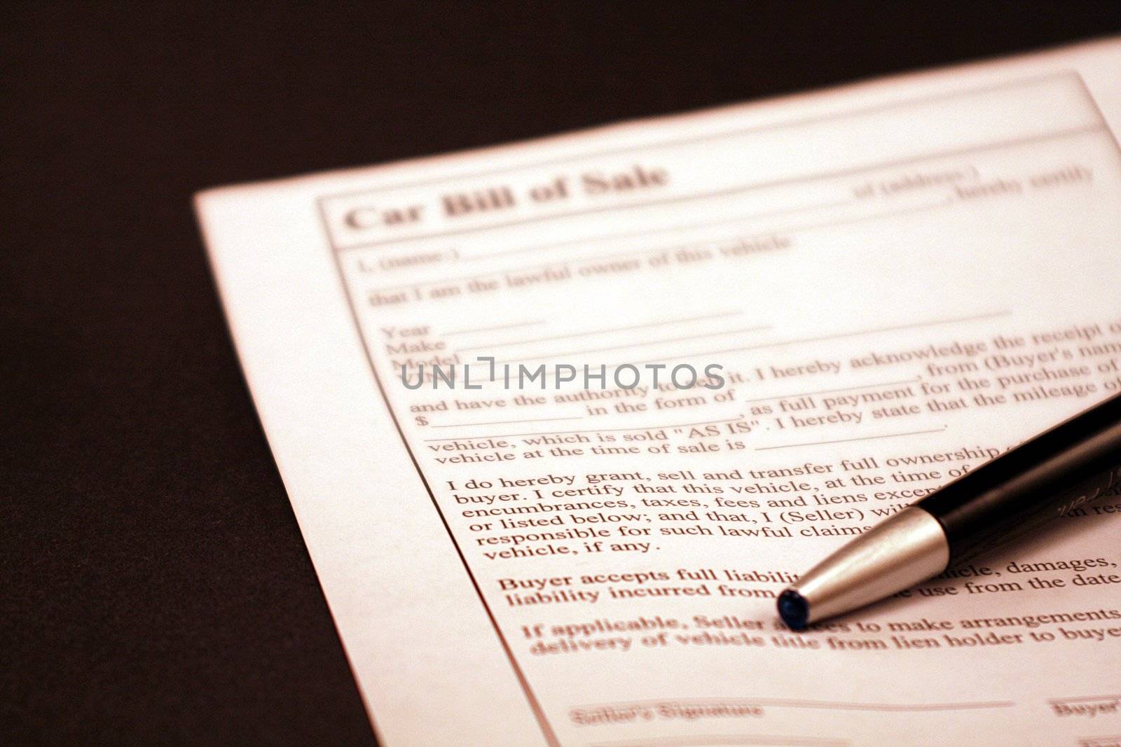 Car bill of sale document on black background. Black and silver ink pen on top of the financial document. Car loan, car sales, car loan opportunities.