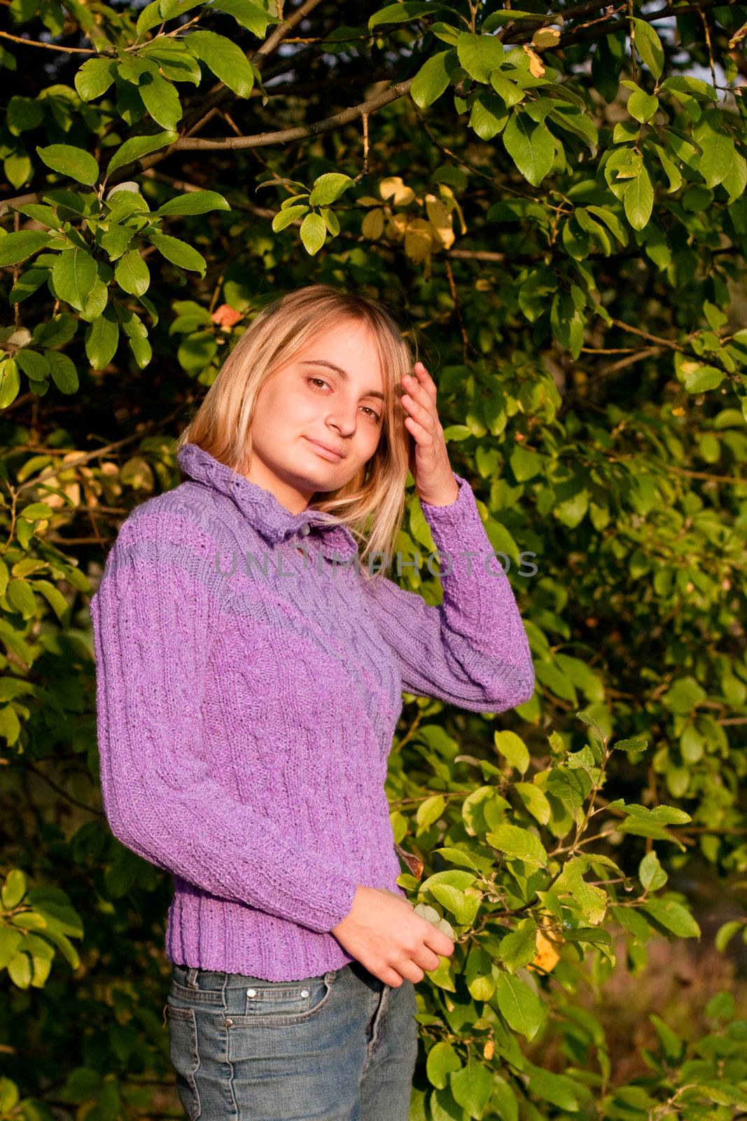 A girl in a lilac pullover and jeans in a forest
