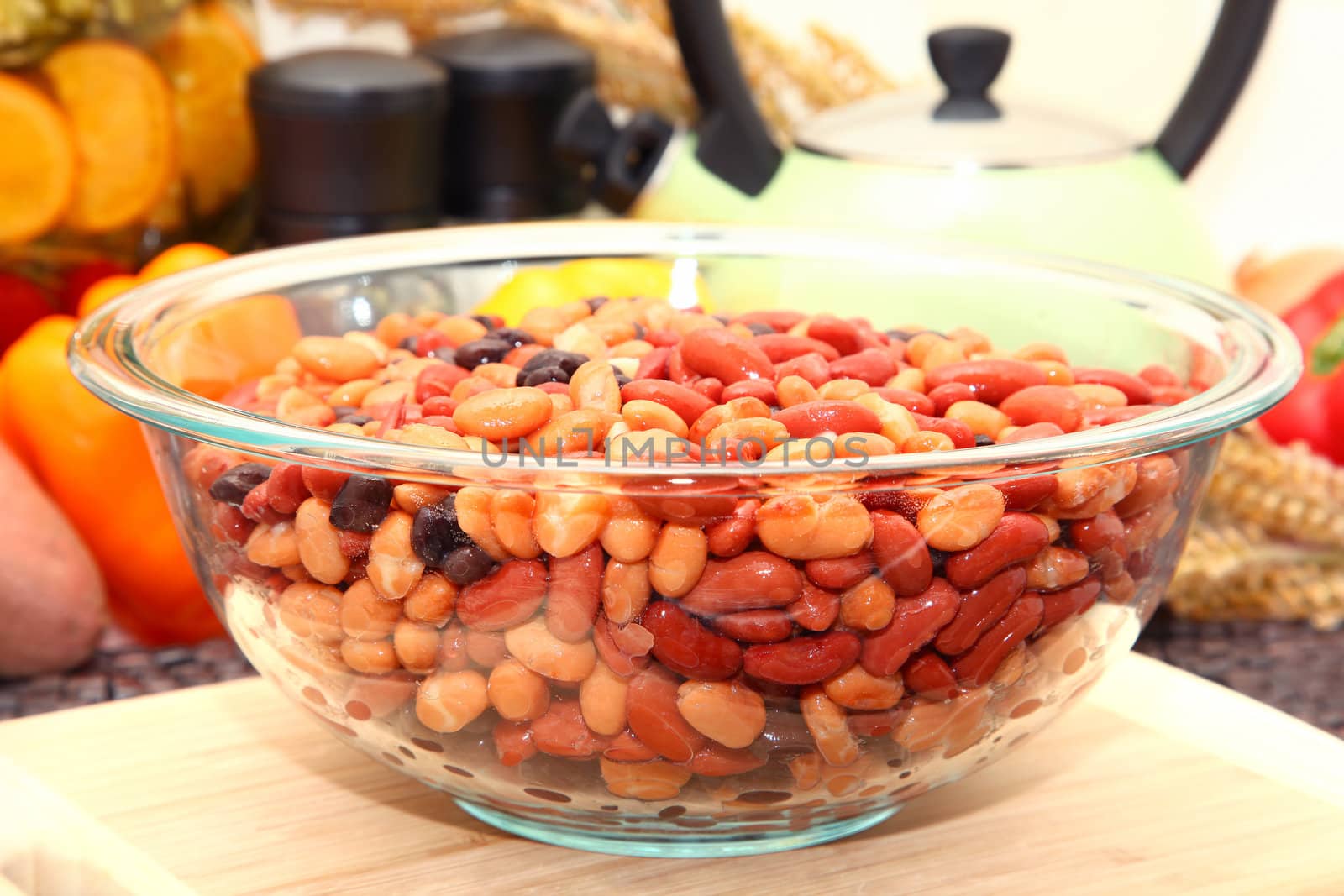 Kidney, pinto and black beans in a glass bowl in kitchen or restaurant.