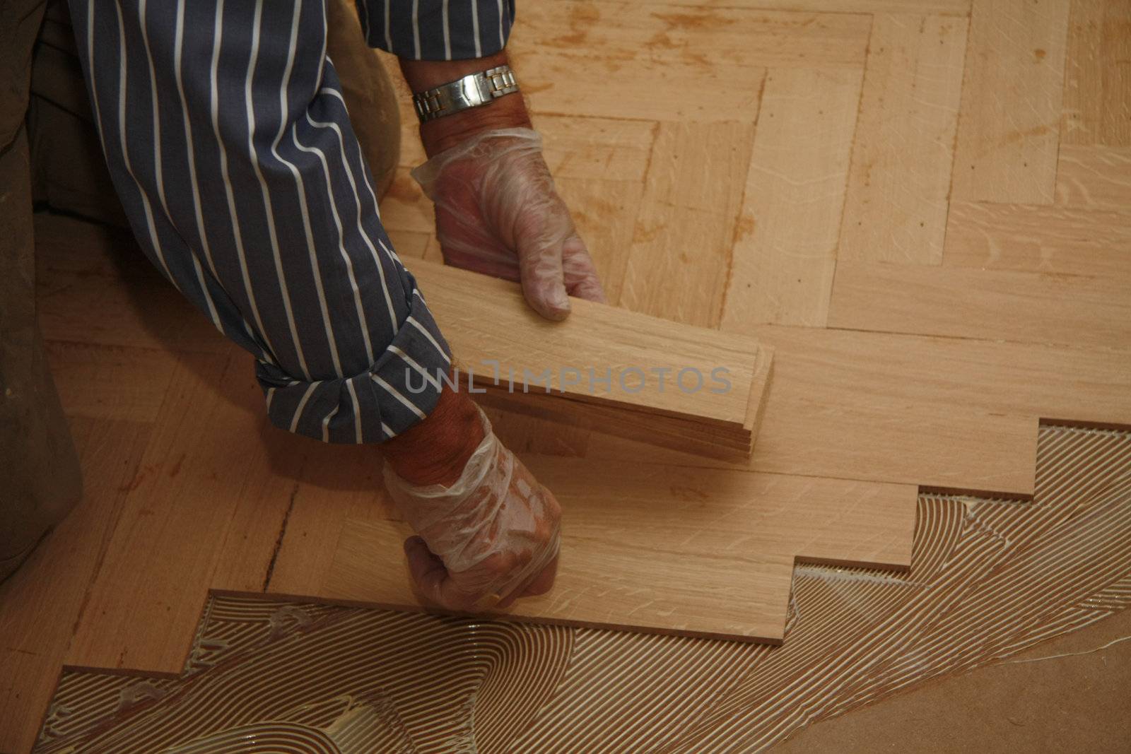 Detail of a man busy laying a wooden floor in fishbone pattern