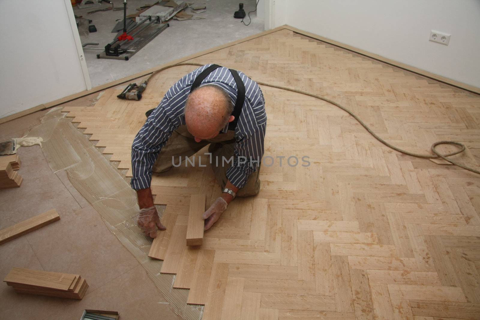 Man laying a wooden parquetry flooring in fishbone pattern