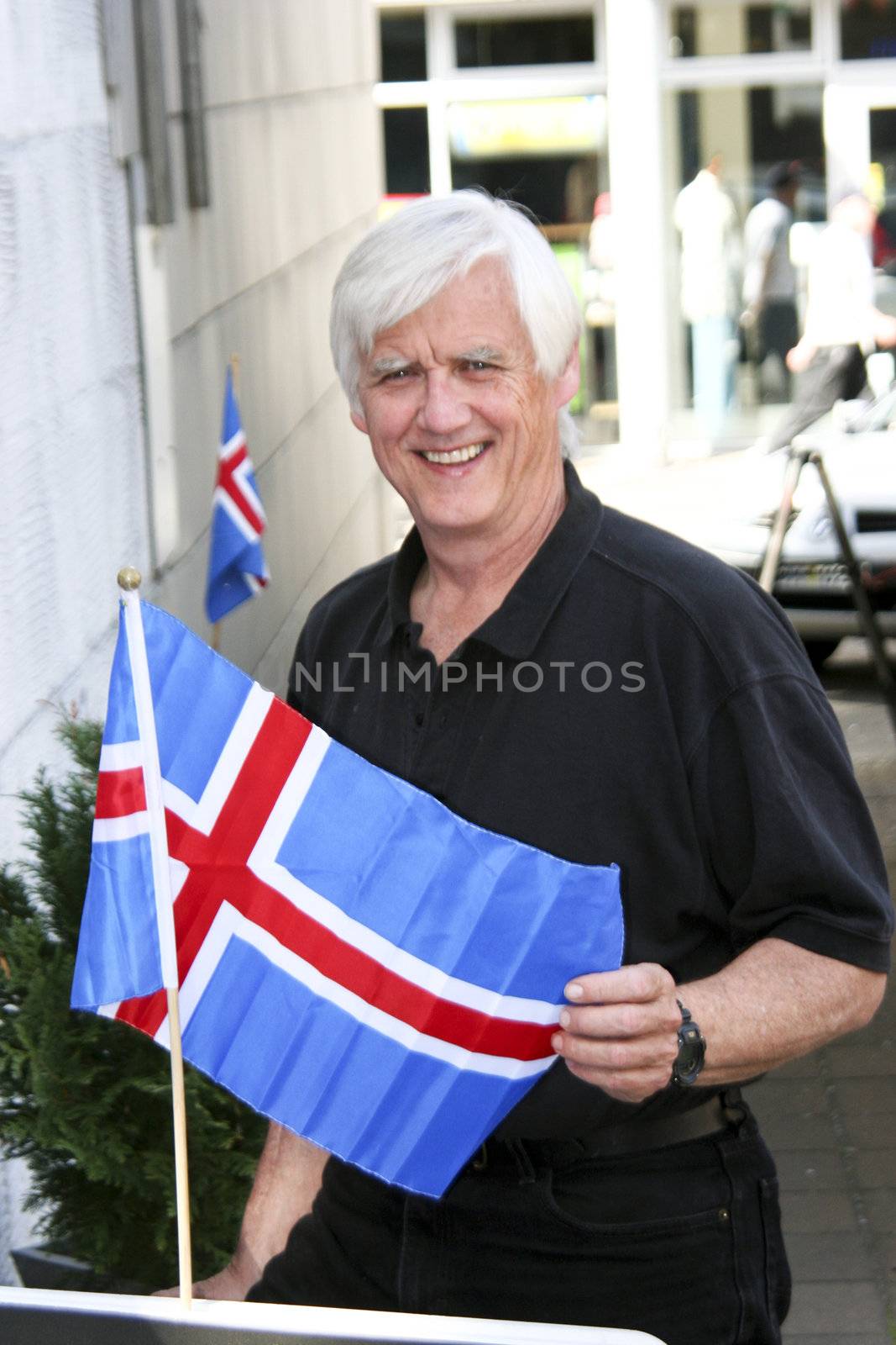 Mature, senior male with table top copy of Iceland's national flag in Reykjavik, Iceland