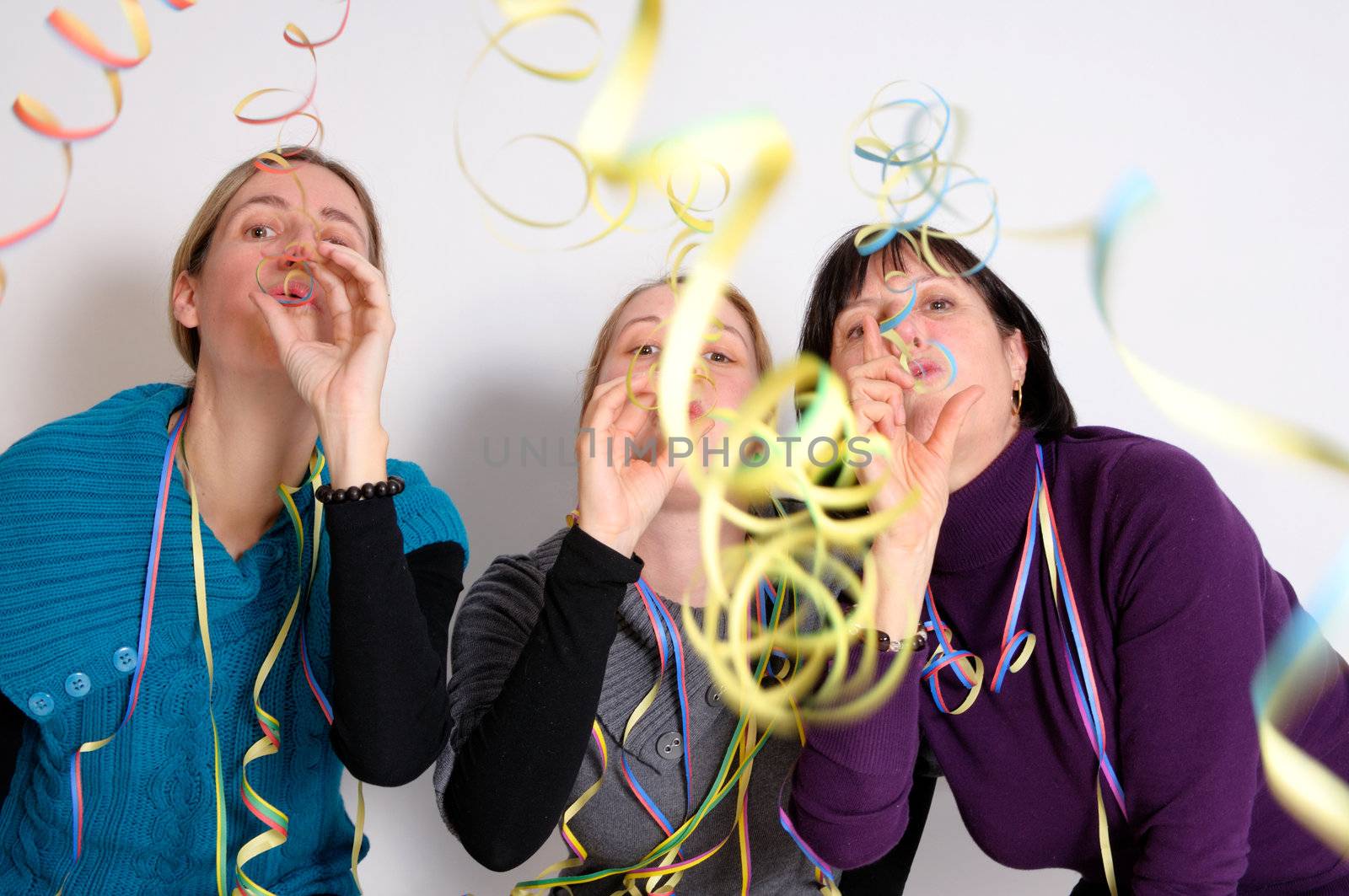 Two young women and one senior woman celebrating New year's eve. Shot taken in front of white background