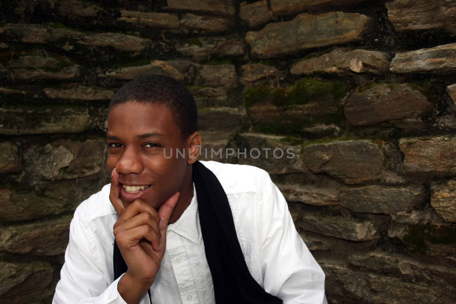 A man in front of mossy wall smiling