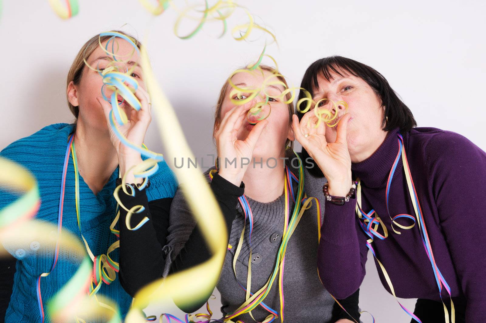 Two young women and one senior woman celebrating New year's eve. Shot taken in front of white background