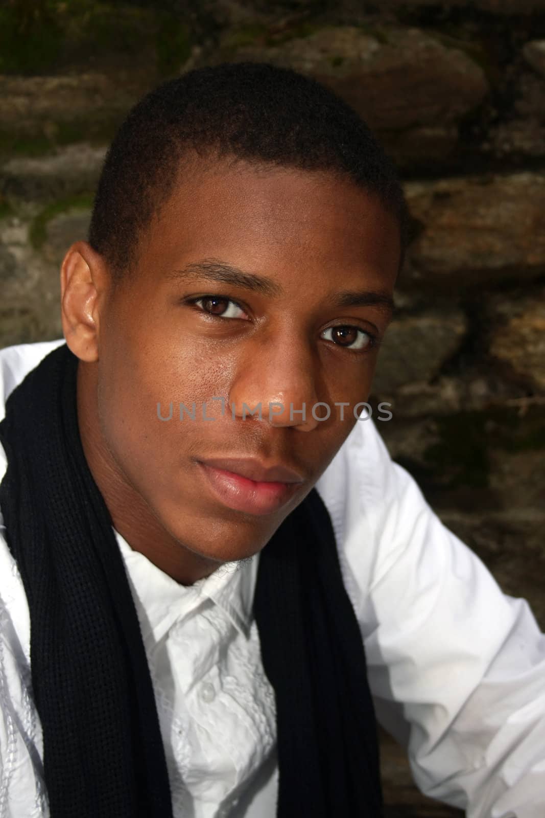 A man dressed in white with black scarf smiling