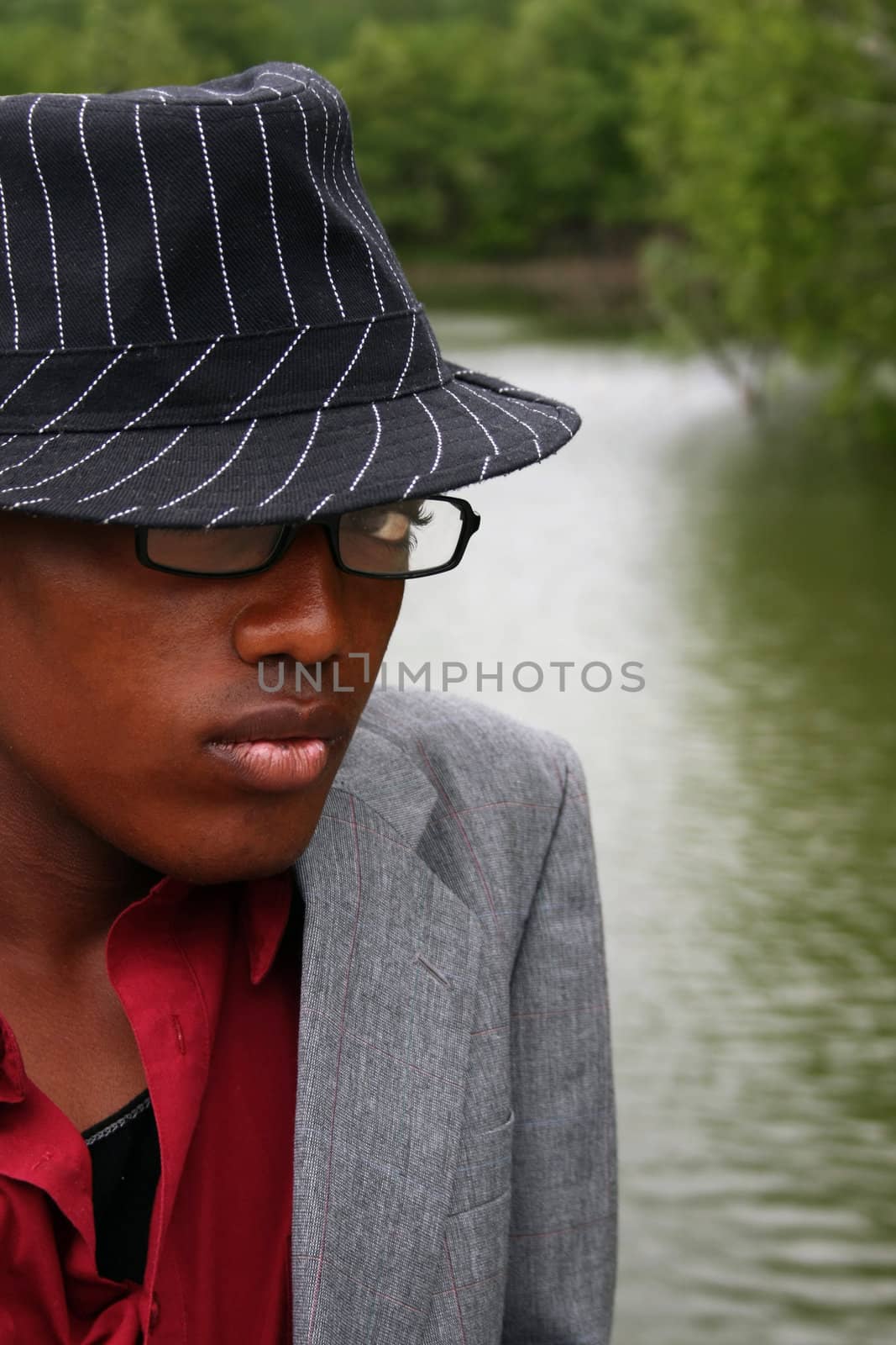 Man with a hat on standing in front of a lake