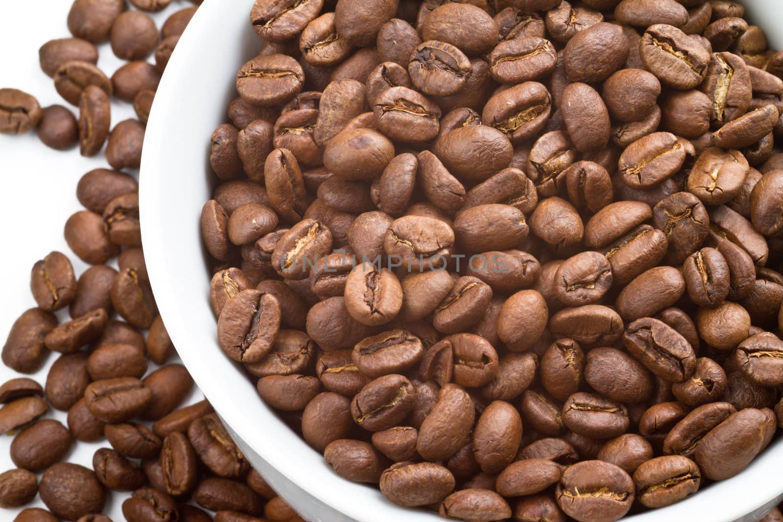 Close up of Coffee beans in and around a white bowl and on white background