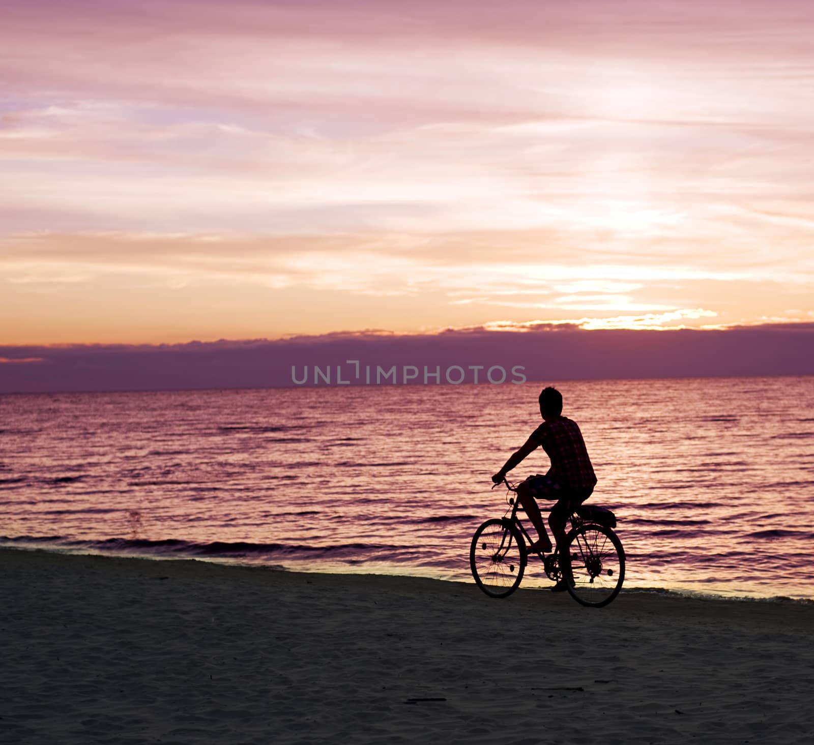 A parson rides by bicycles on the Baltic sea beach