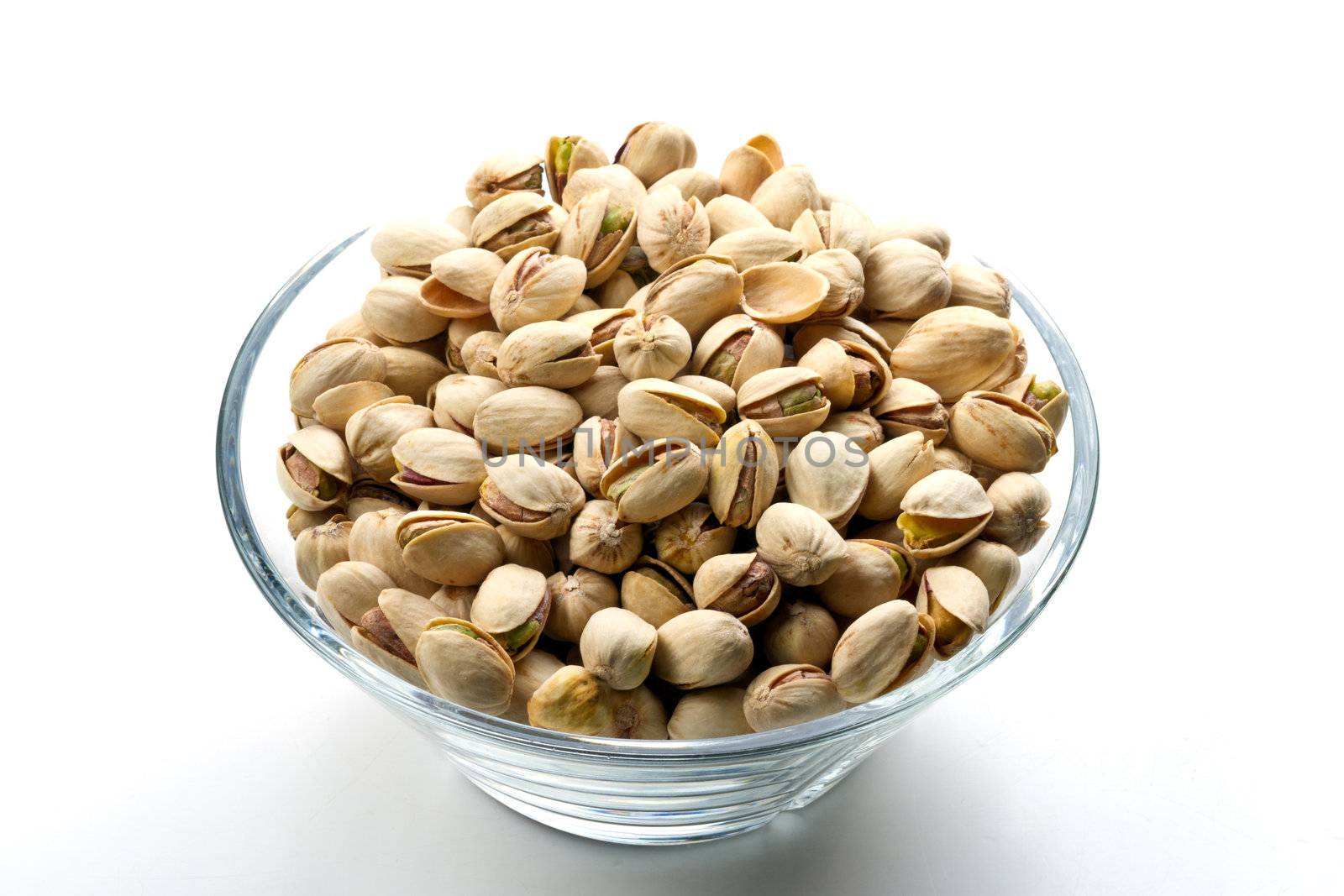 Pistachios nuts in glass bowl with white background