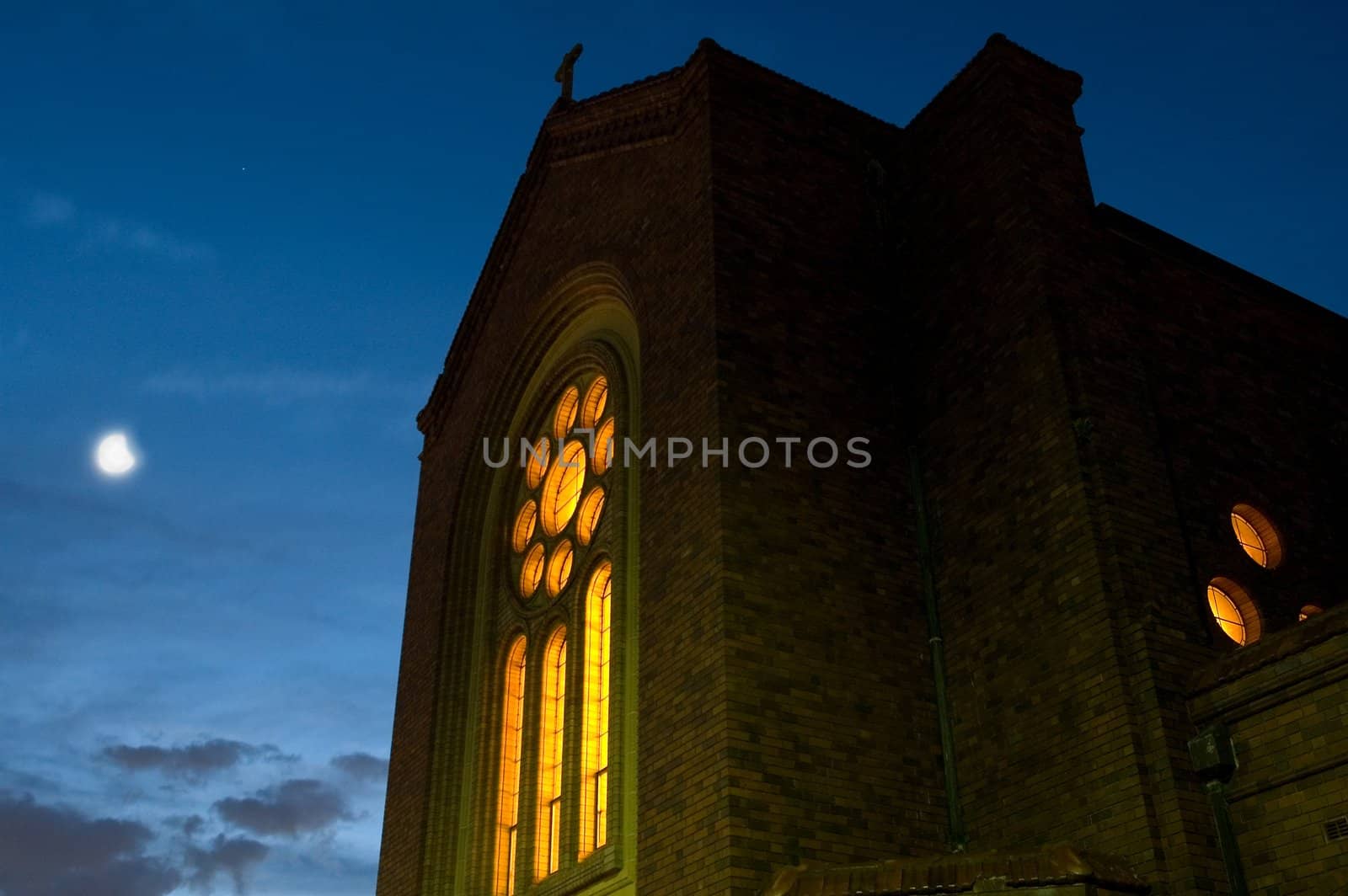 church in sydney at night, illuminated from inside, moon in background