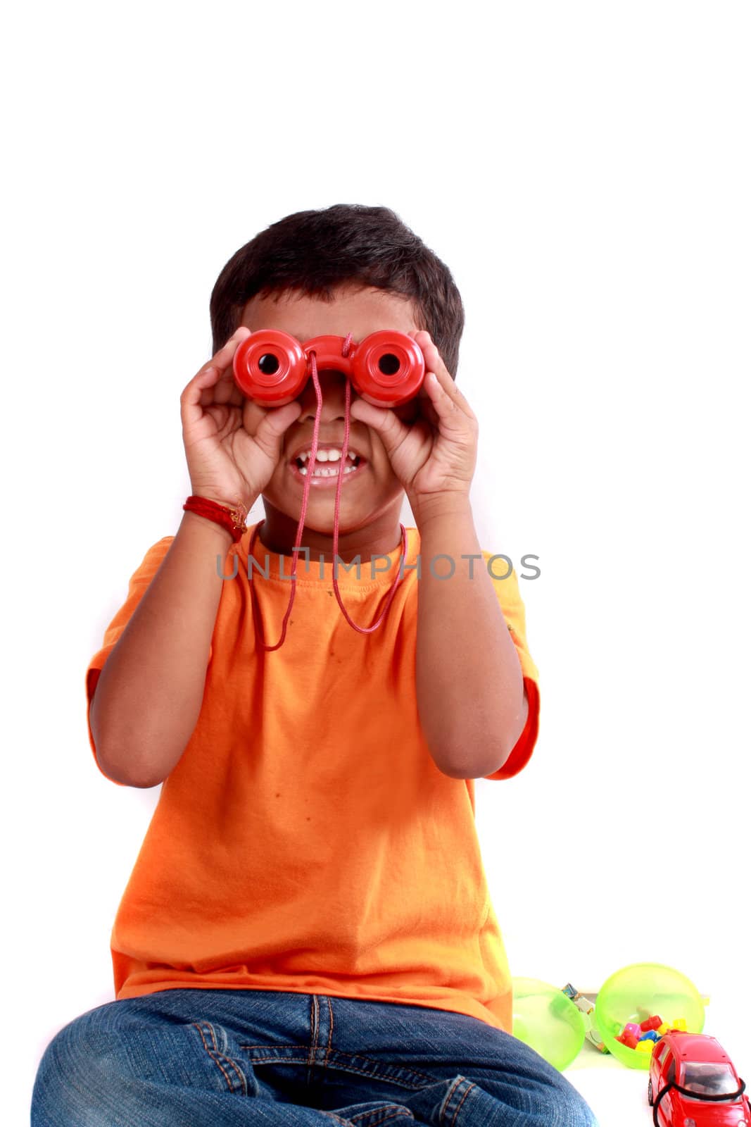 A cute Indian kid looking through red binoculars.