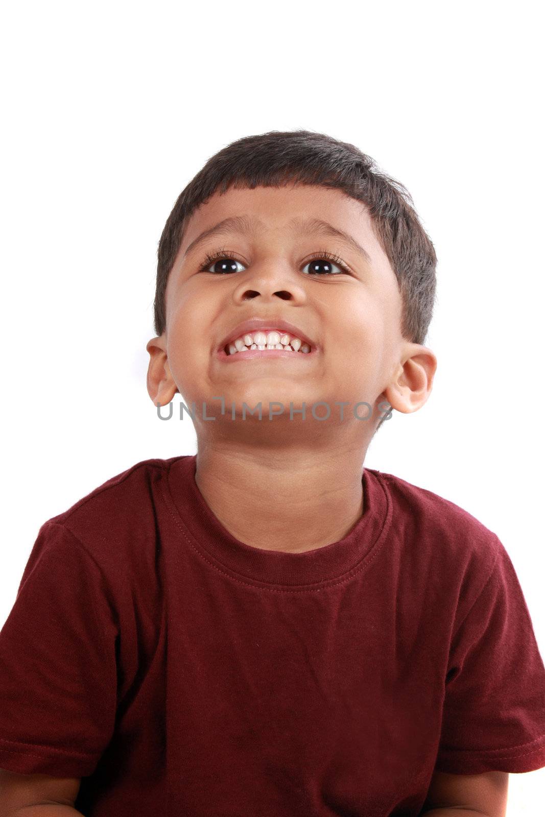 A portrait of a cute Indian boy showing his teeth, on white studio background.