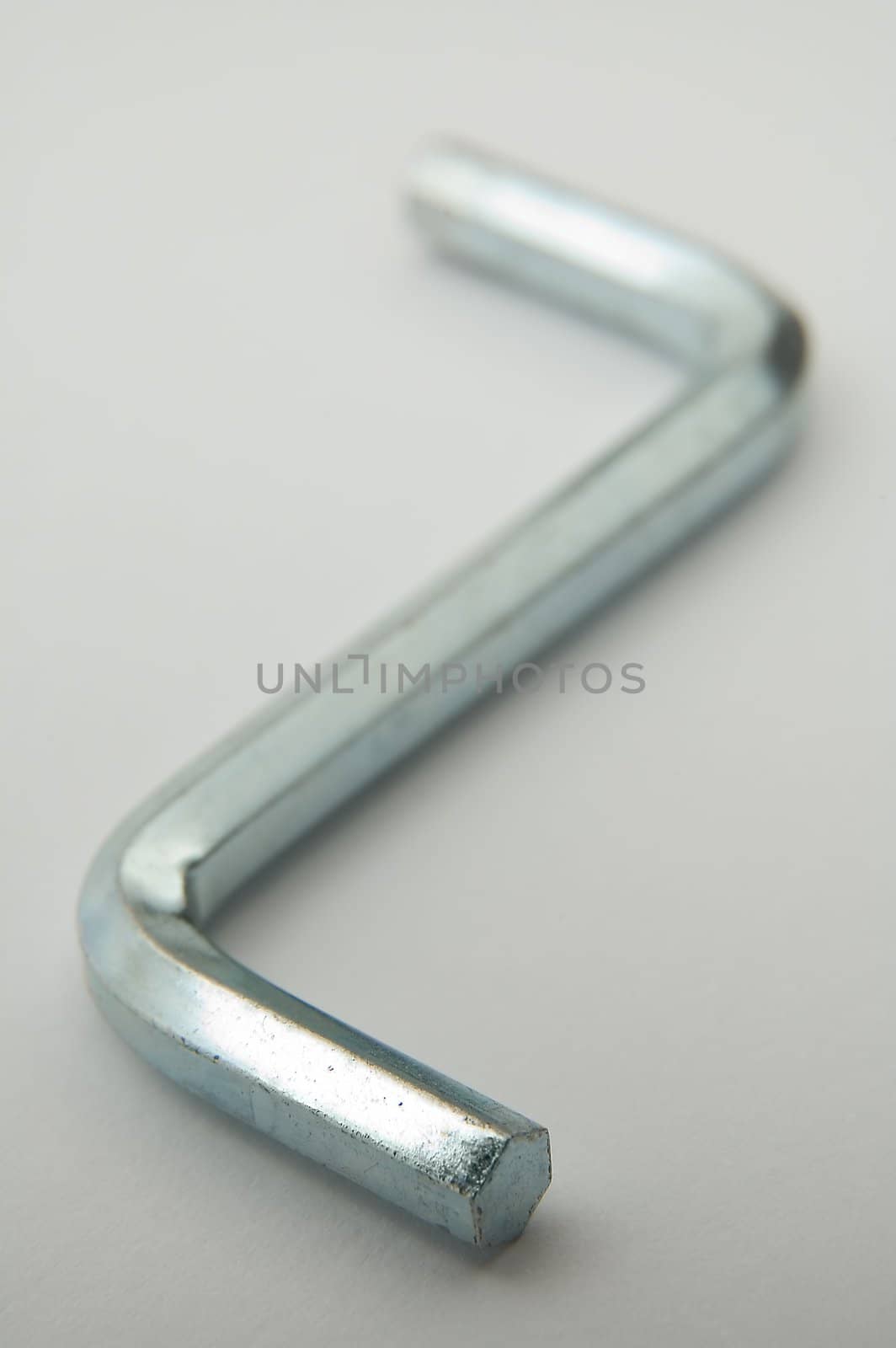 steel shiny hex key on grey background, distance blur
