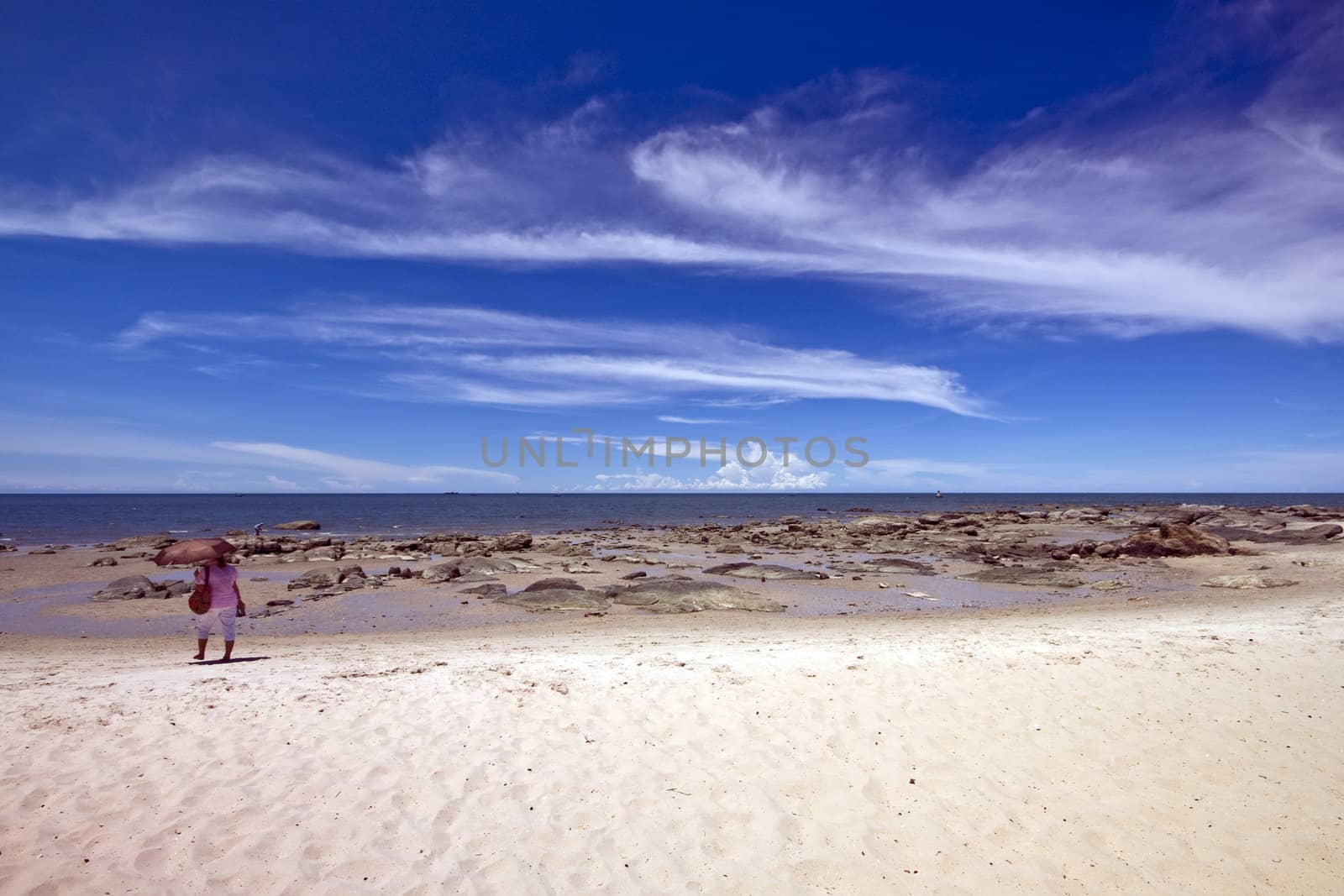 Woman with umbrella on Hua Hin beach