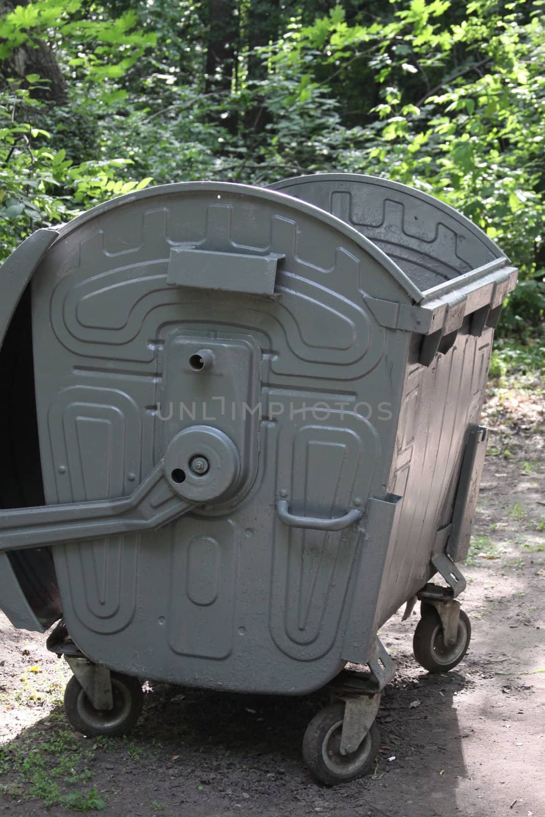 Recycle can on a sidewalk in a park.