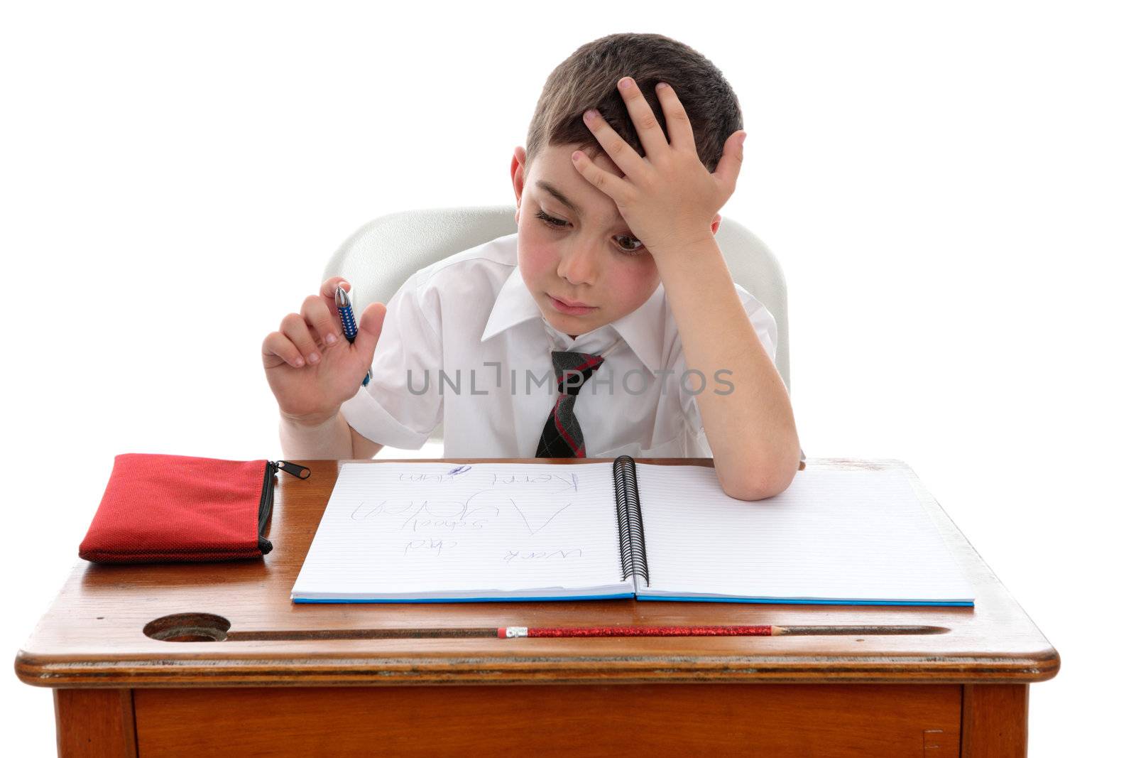 A young schoolboy sitting at a school desk in deep thought or having a problem or difficulty.   White background