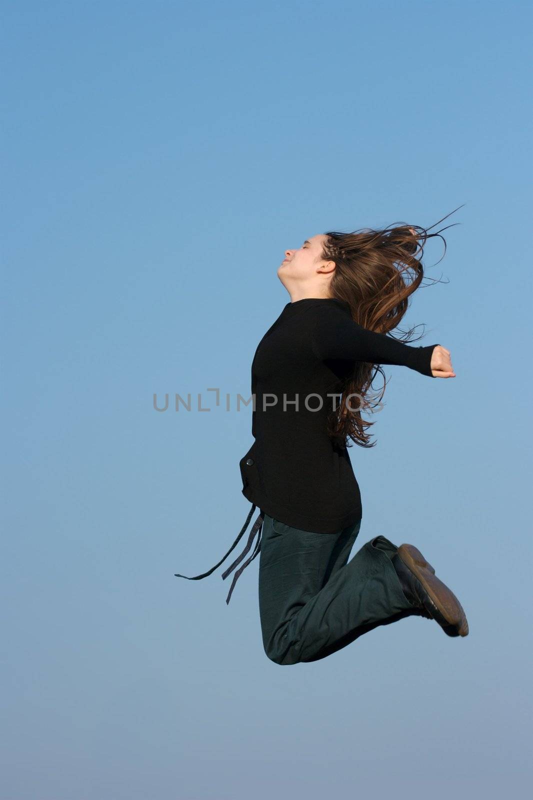 Happy girl jumping against clear blue sky