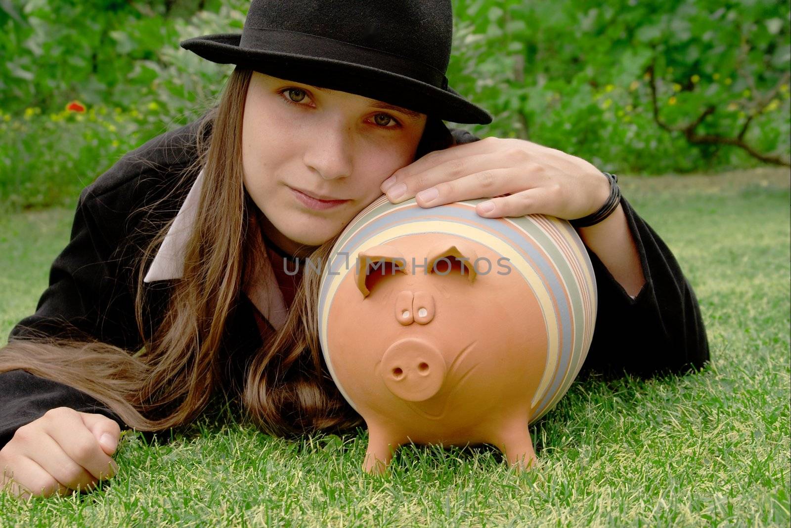 Girl lying in the grass with a piggy bank