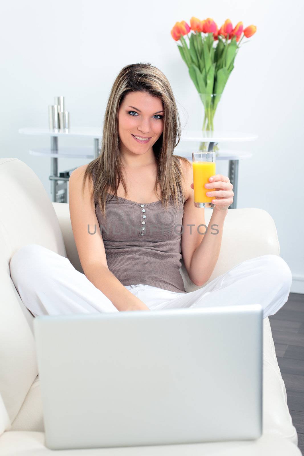 woman on sofa with laptop and orange juice