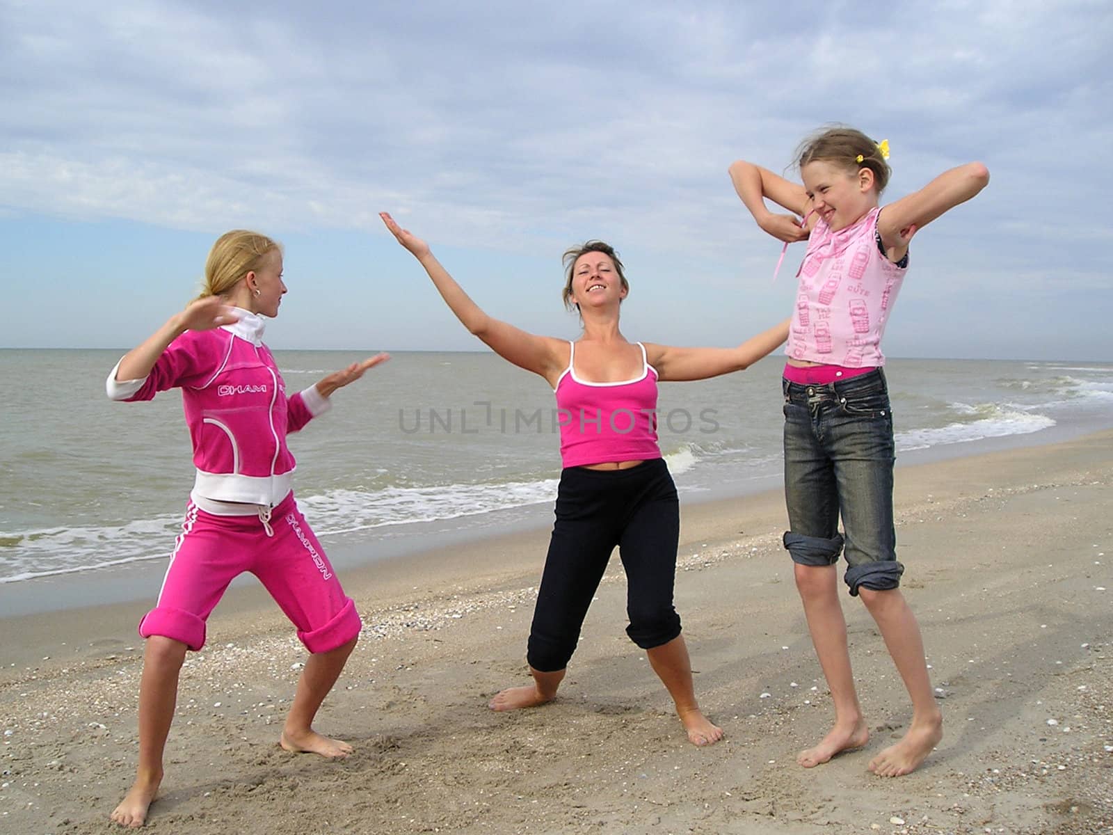 three girls they dance on the shore Azov sea during the summer sunny day. 