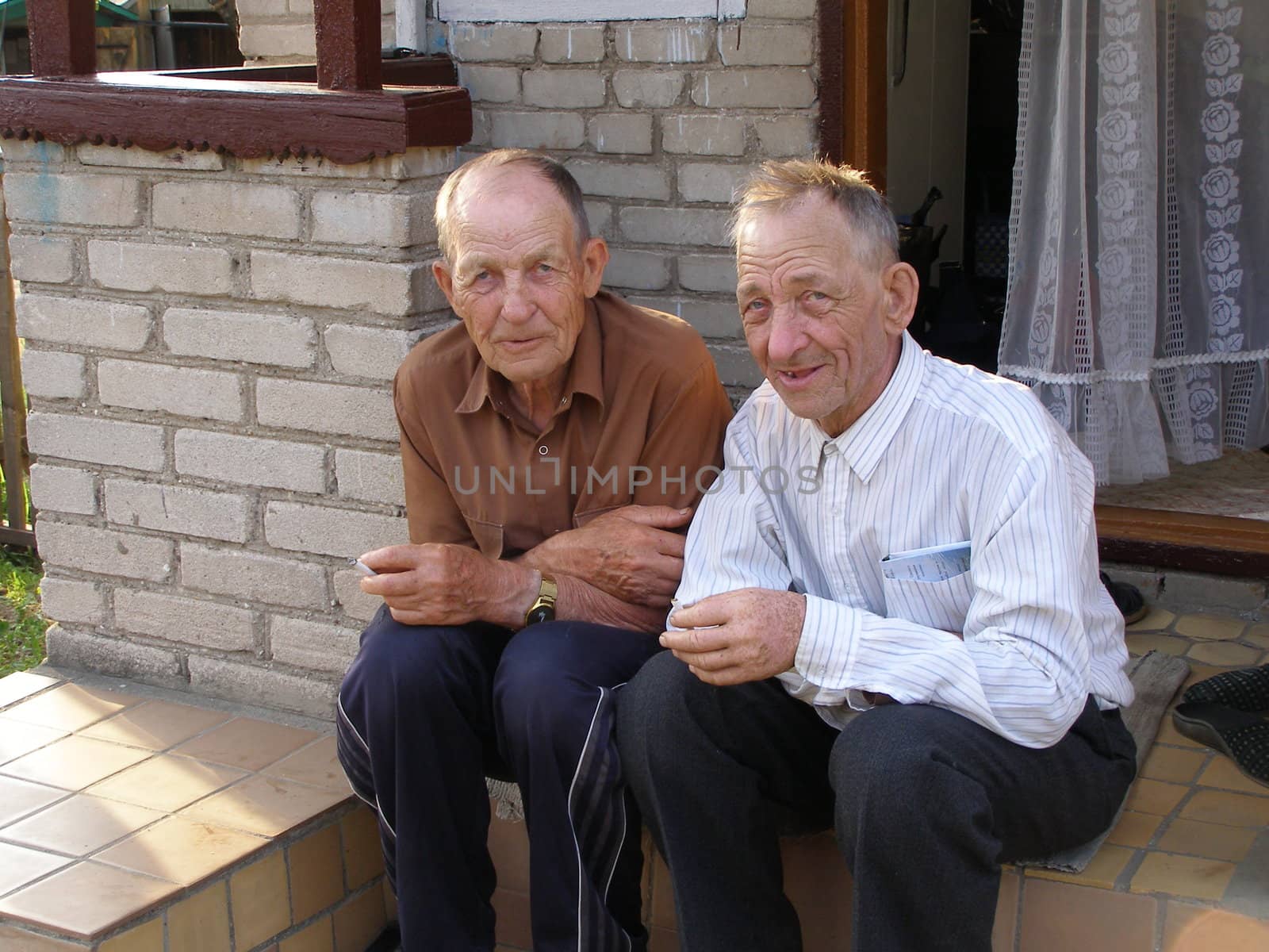 two brother, old men, sit on the stairs of house and recall their young years. 
