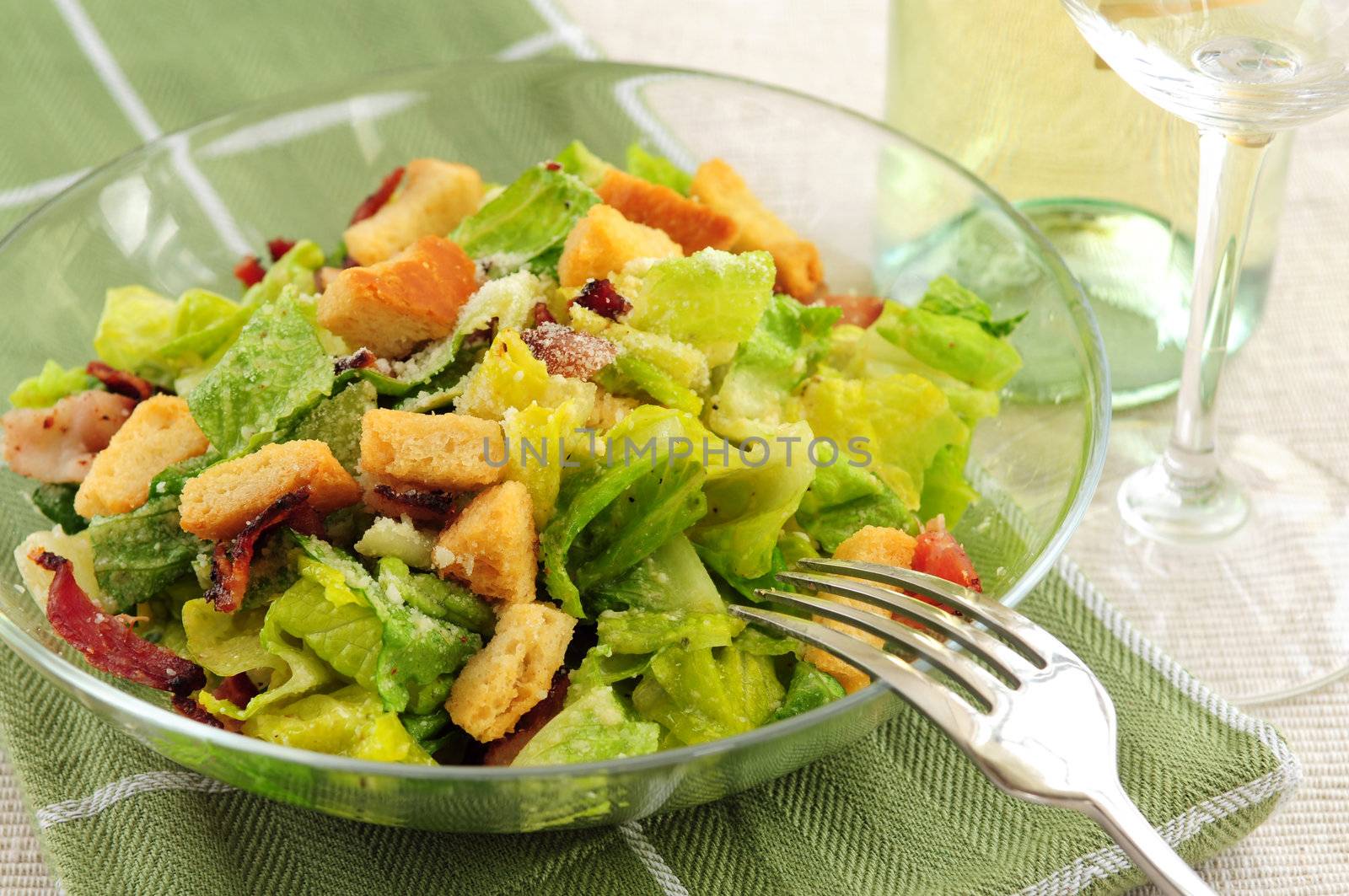 Caesar salad served in a glass bowl and white wine