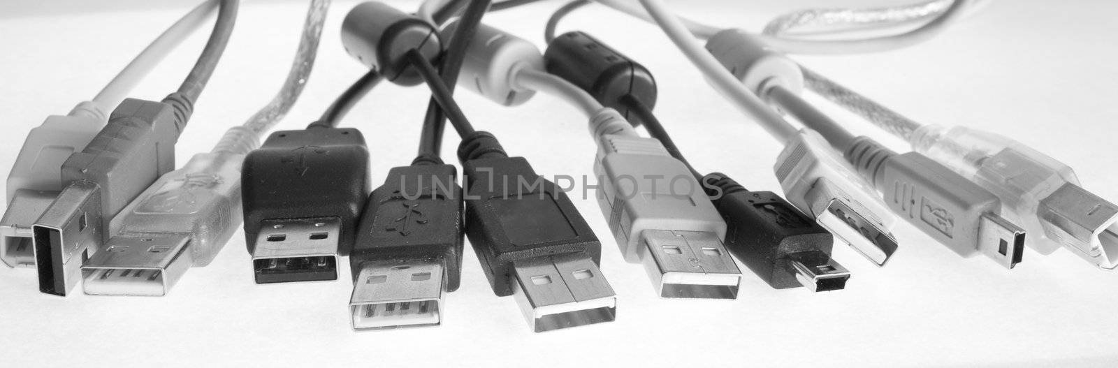 USB cables with plugs lay in a number(line), wires are chaotically bound