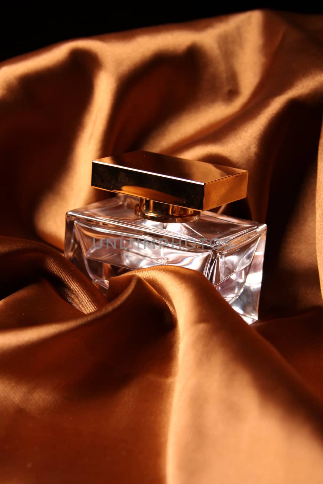 Unique parfume bottle over luxury silk background.