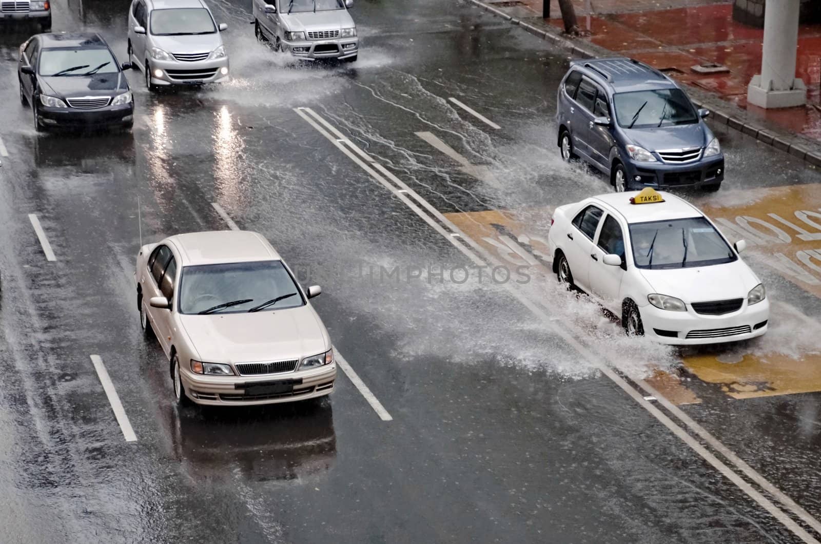 Car driving through a flooded street with huge splash