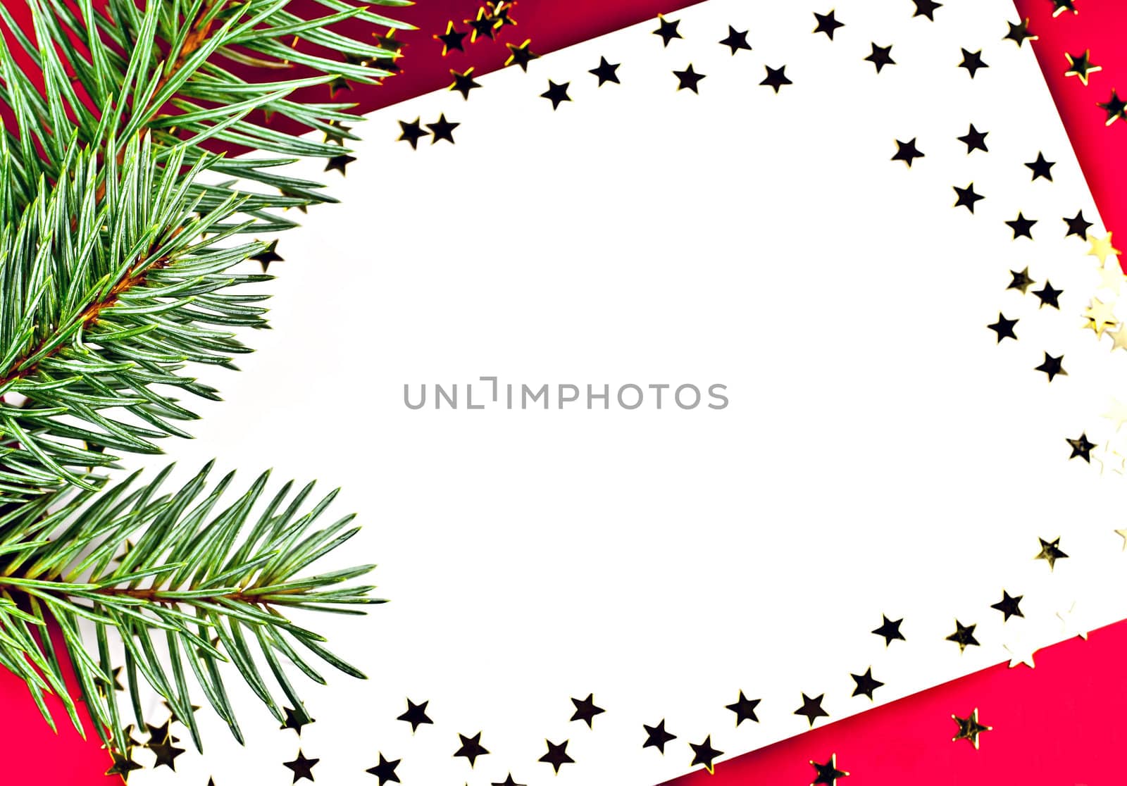 On a red background white greeting card with spruce twigs and golden stars.