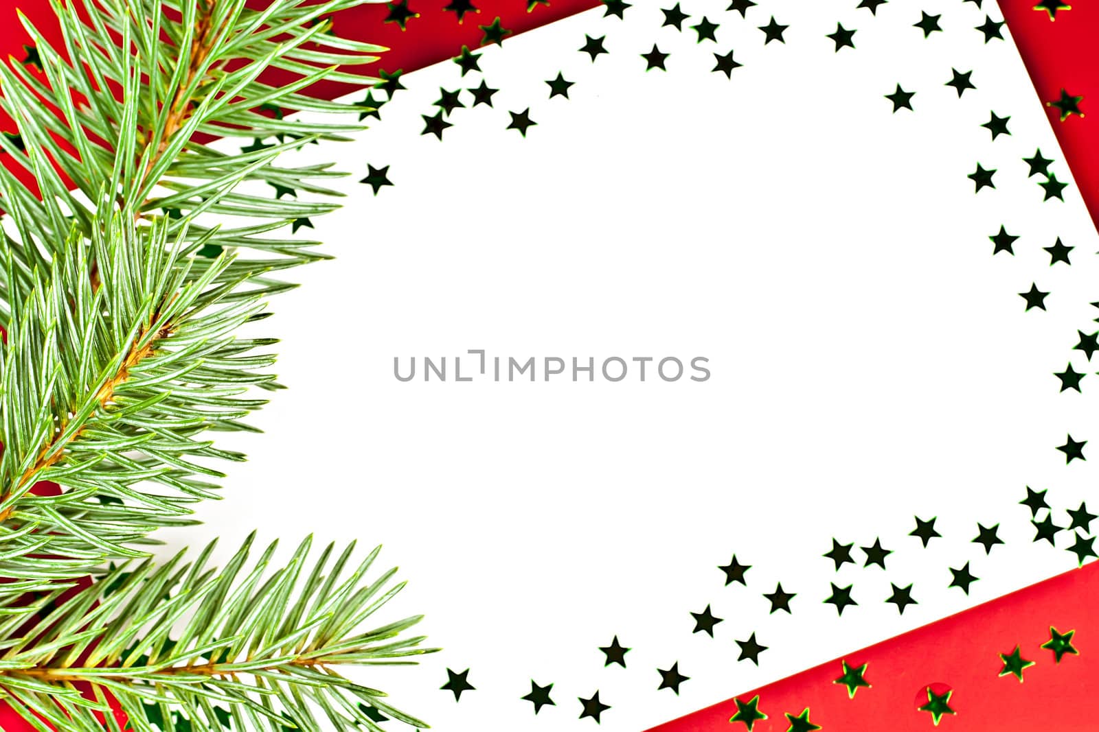 On a red background white greeting card with spruce twigs and green stars.
