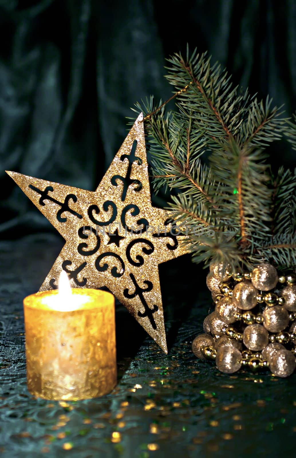 Christmas composition, candle, fir branch and star on a green background.
