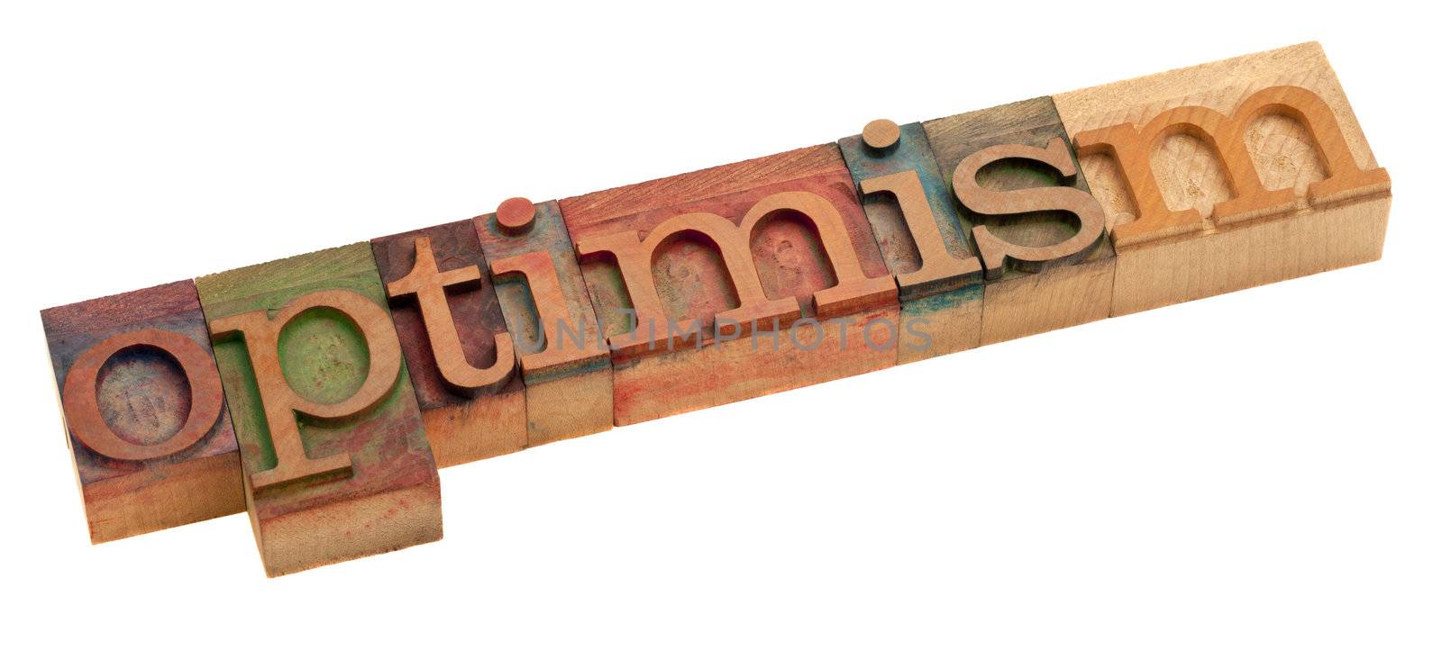 optimism word in vintage wooden letterpress printing blocks, stained by color inks, isolated on white