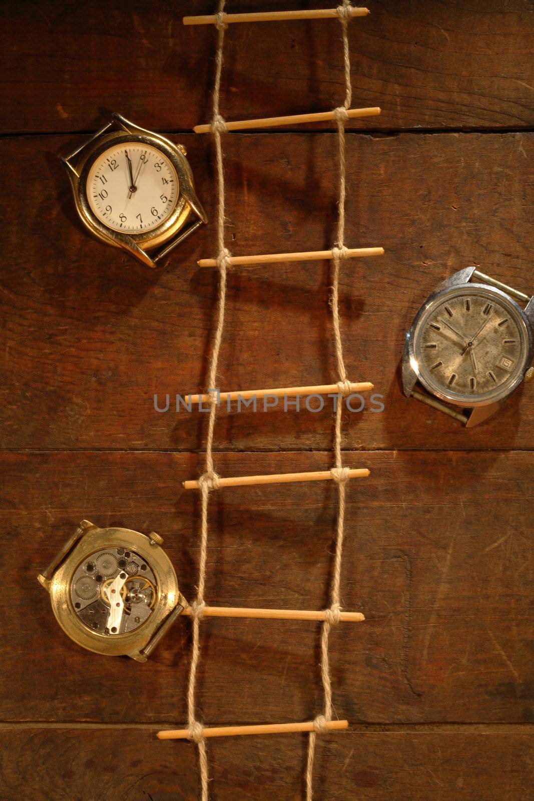 Rope ladder hanging on wooden background with old watches