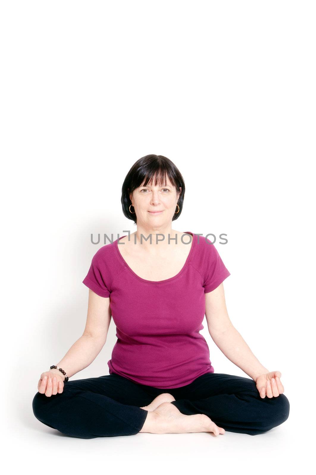 Aged woman sitting in lotus seat practicing yoga.